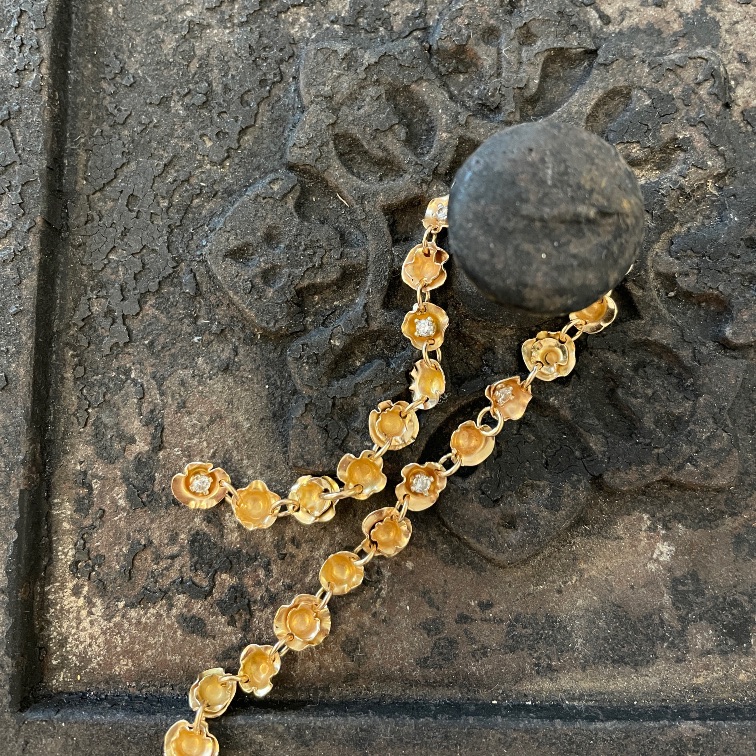 Goldfarbenes Collier aus verbundenen Blütenelementen auf einer strukturierten Metallfläche